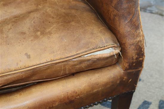 A George III mahogany hide-covered wing chair